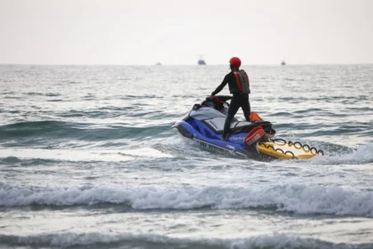 Motoscafo ad alta velocità in mare vicino a una spiaggia affollata con bagnanti