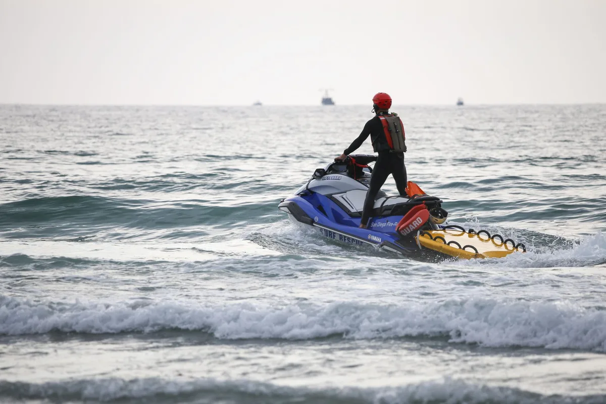 Motoscafo ad alta velocità in mare vicino a una spiaggia affollata con bagnanti