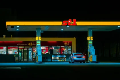 Mano anonima che inserisce la pompa di carburante al distributore con display prezzi illuminato