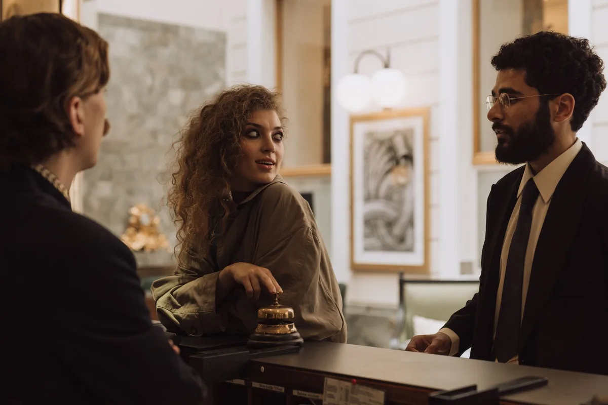 Bancone di una reception d'albergo con ospiti in attesa di check-in