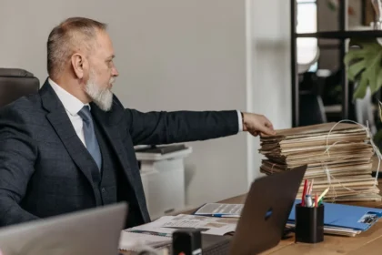 Persona anonima che lavora con documenti e cartelle amministrative su una scrivania in ufficio