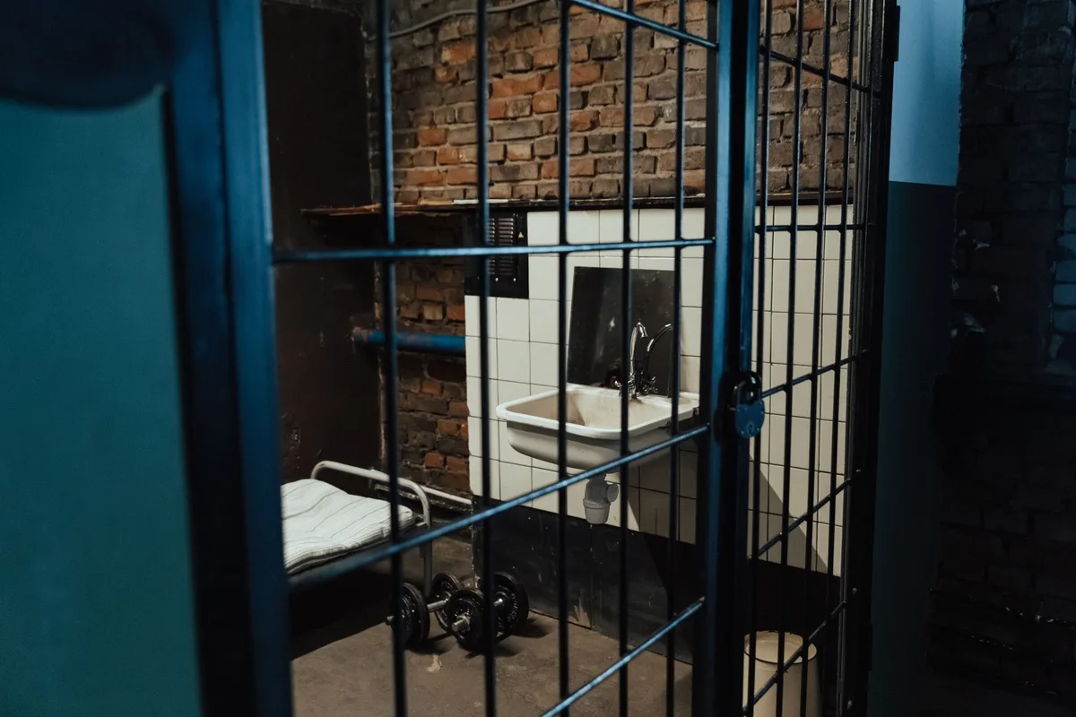 Dettagli di una cella carceraria con elementi metallici e lavandino