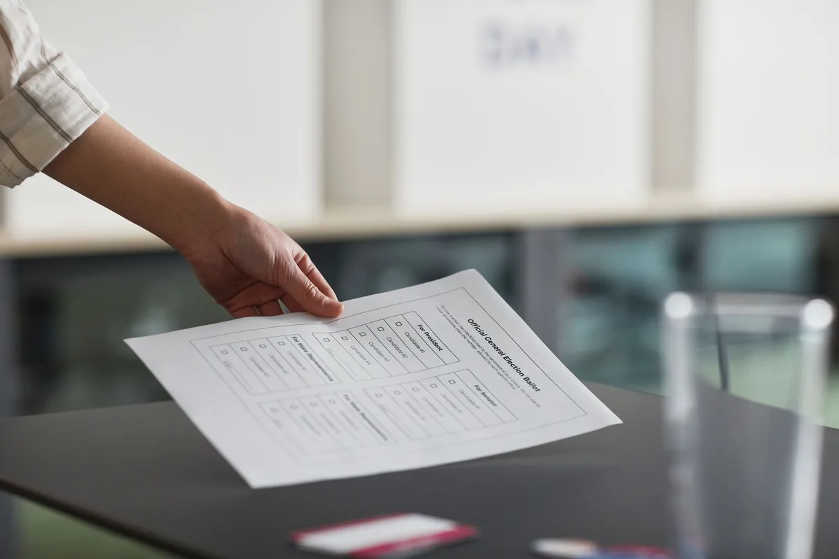 Mano che inserisce una scheda di voto in un'urna durante una consultazione elettorale