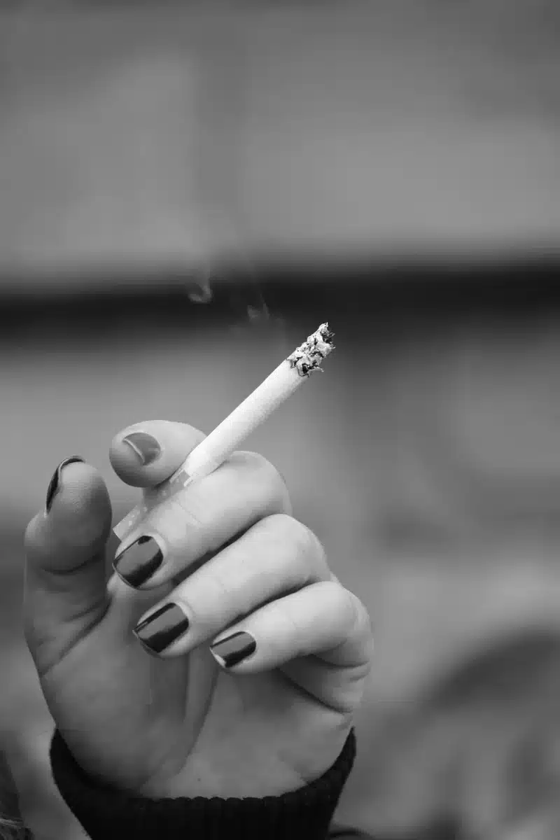 Mani anonime che ordinano foglie di tabacco su un tavolo in fattoria