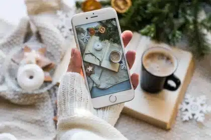 Mani che tengono uno smartphone con icona di tessera digitale vicino a una tessera cartacea su un tavolo del seggio