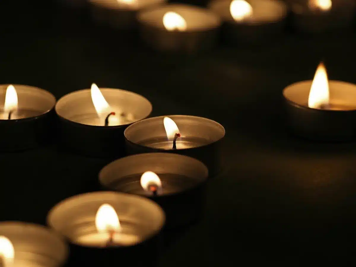 Mani anonime che depositano fiori e una candela in un memoriale cittadino