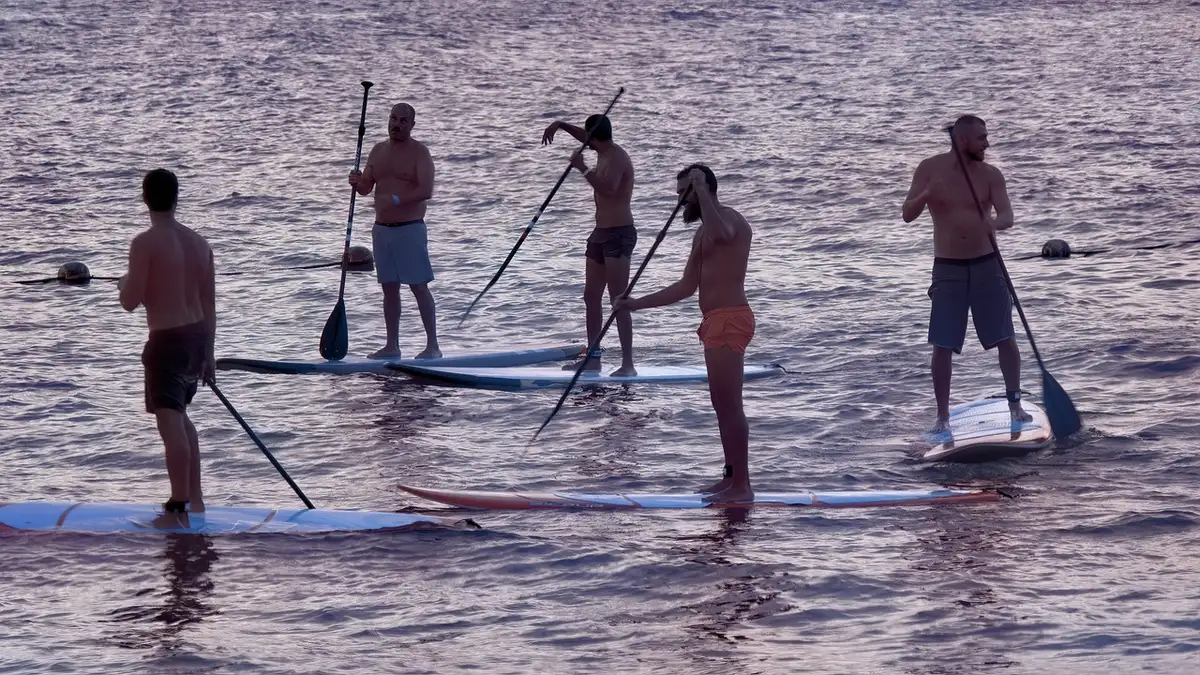 Tavolo con mappe e radio vicino a una strada costiera su un'isola, persone anonime in silhouette