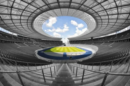 Pallone da calcio sulle mani davanti a una panchina e rete vuote